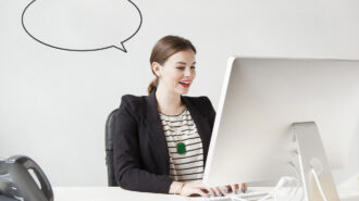 Studio shot of young woman working on computer with speech bubble next to her head