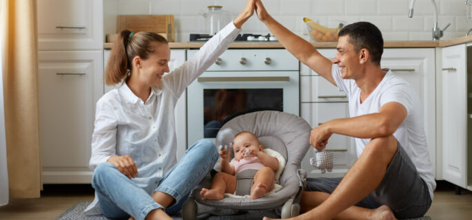 full-size-photo-positive-three-people-mommy-daddy-small-kid-girl-boy-bouncer-parents-make-hands-roof-enjoying-sit-floor-light-kitchen-indoors